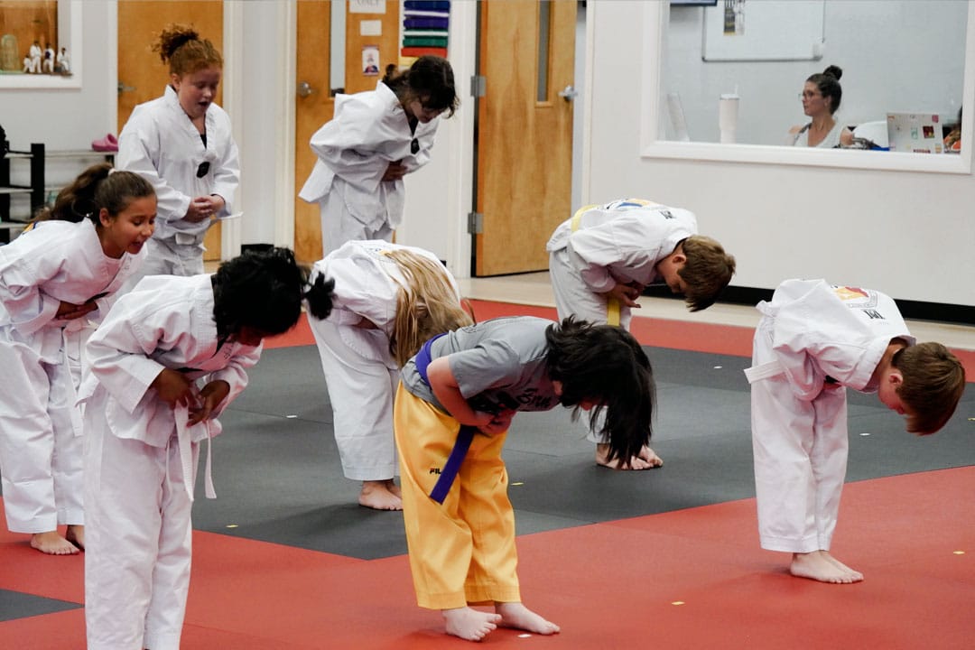 Kids martial arts class ages 7&ndash;12 bowing together to practice discipline, respect, and self-control in Peachtree City