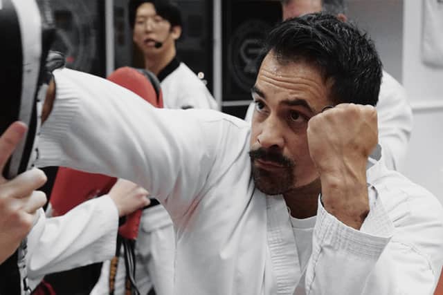 Adult martial arts student training with focus and power during pad work.