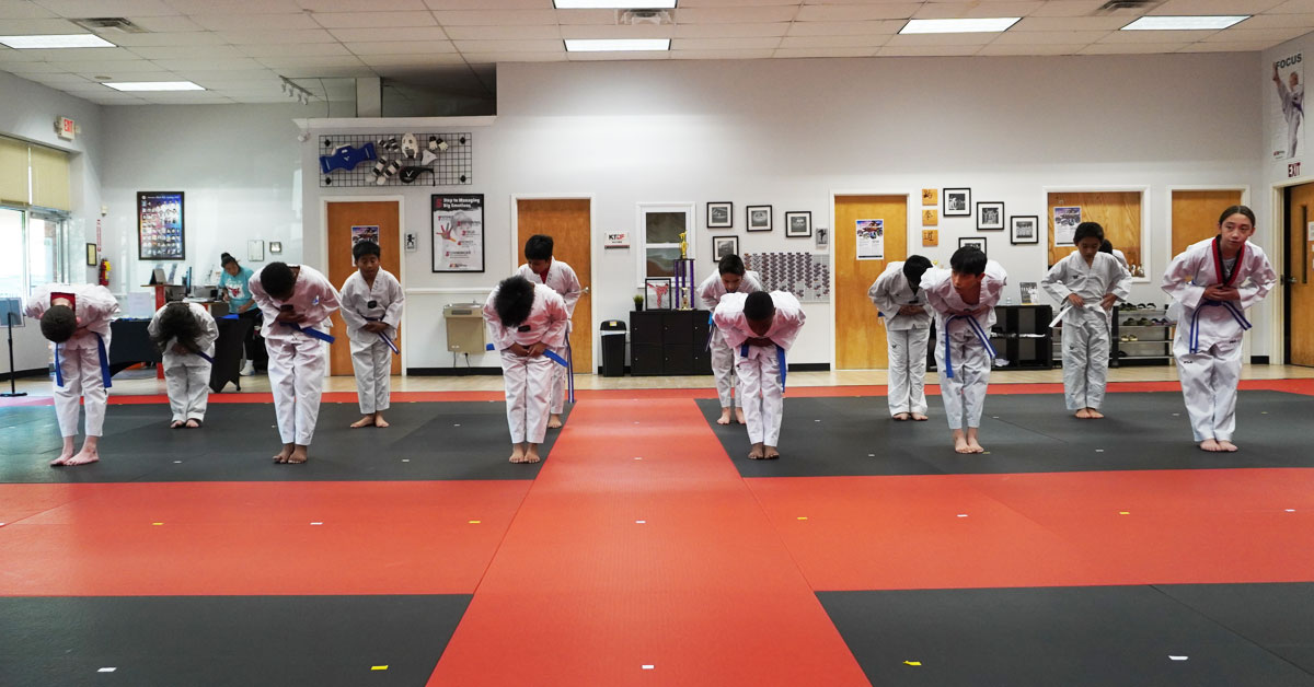 Children in Taekwondo uniforms bowing to show respect and discipline &ndash; long-term bullying prevention strategies | Peachtree City martial arts school
