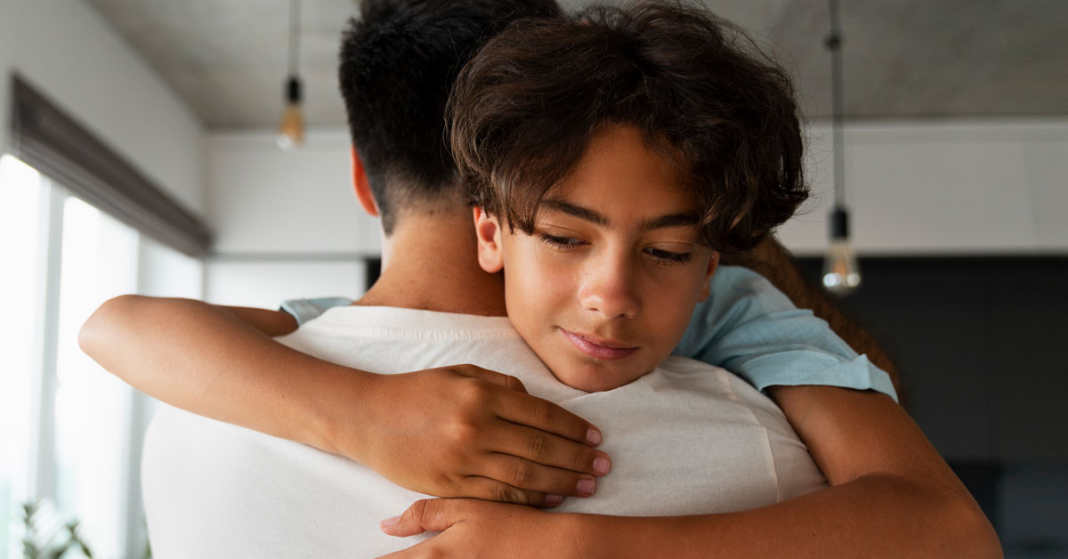 Father hugging son to provide comfort and support &ndash; communicating effectively with your child about bullying | Taekwondo school Peachtree City
