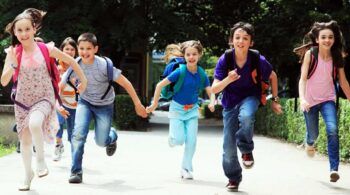 Group of smiling kids with backpacks running outdoors on their first day back to school in Peachtree City