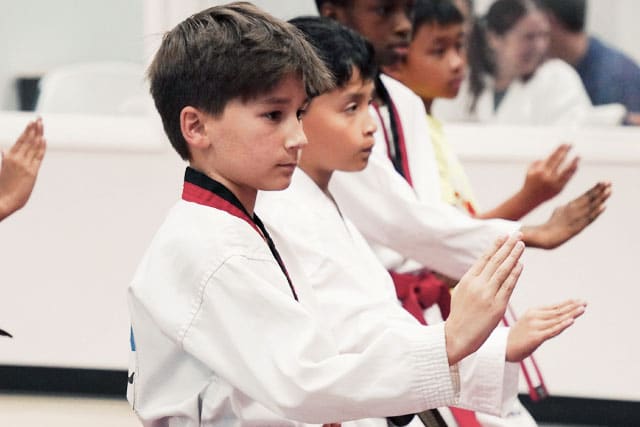 Kids ages 7&ndash;12 practicing focused martial arts techniques during class.