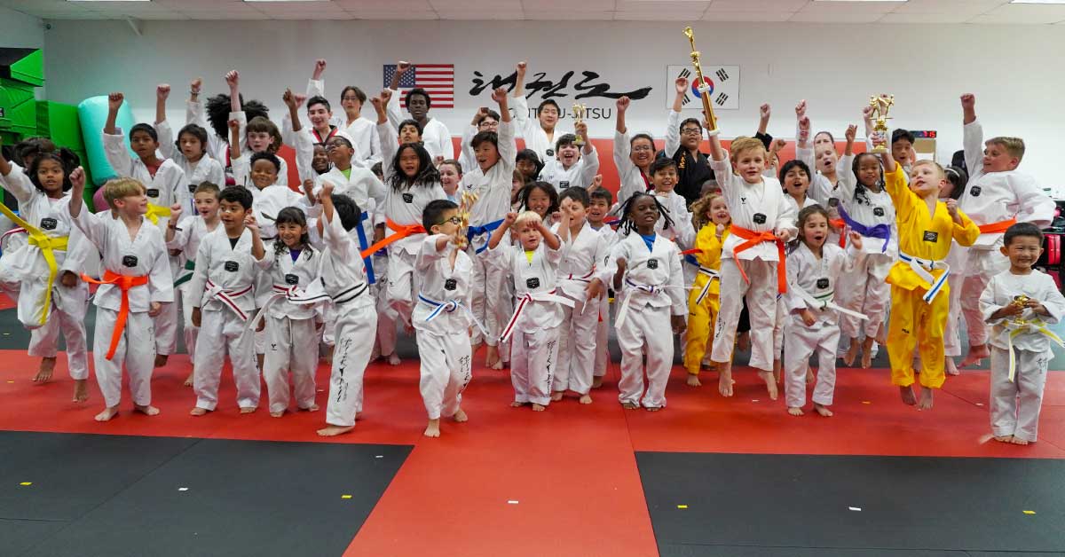 Group of kids in martial arts uniforms celebrating and posing for a photo