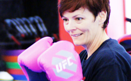 Smiling mom in boxing gloves posing in guard stance during taekwondo class in Peachtree City