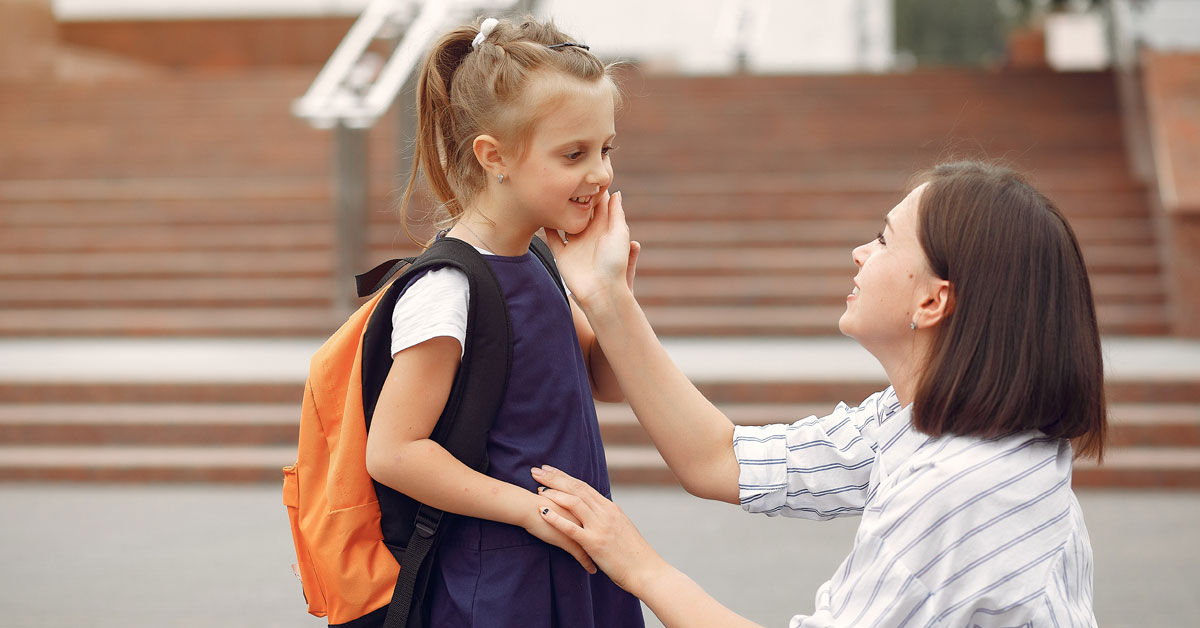 Mother encouraging her daughter before school, wearing a backpack