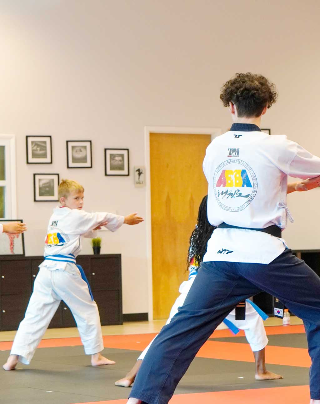 a kid is learning a movement in taekwondo class