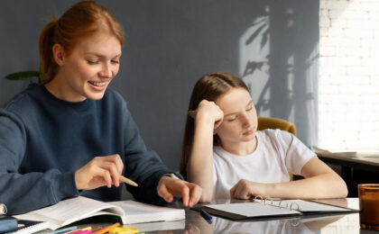 Tired student getting homework help from a smiling teacher at the table